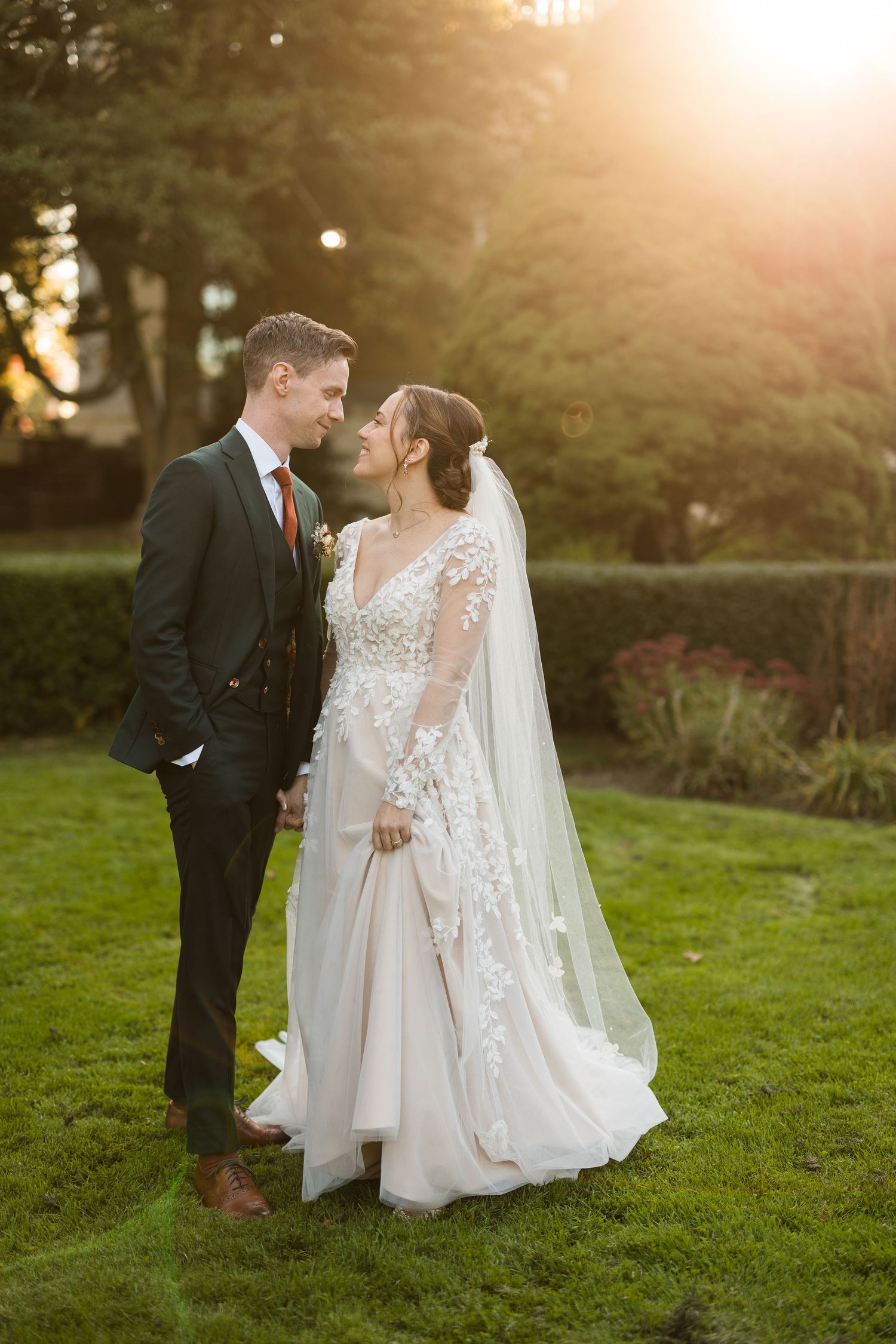 A couple shares an intimate moment at sunset in a garden setting with beautiful golden light.
