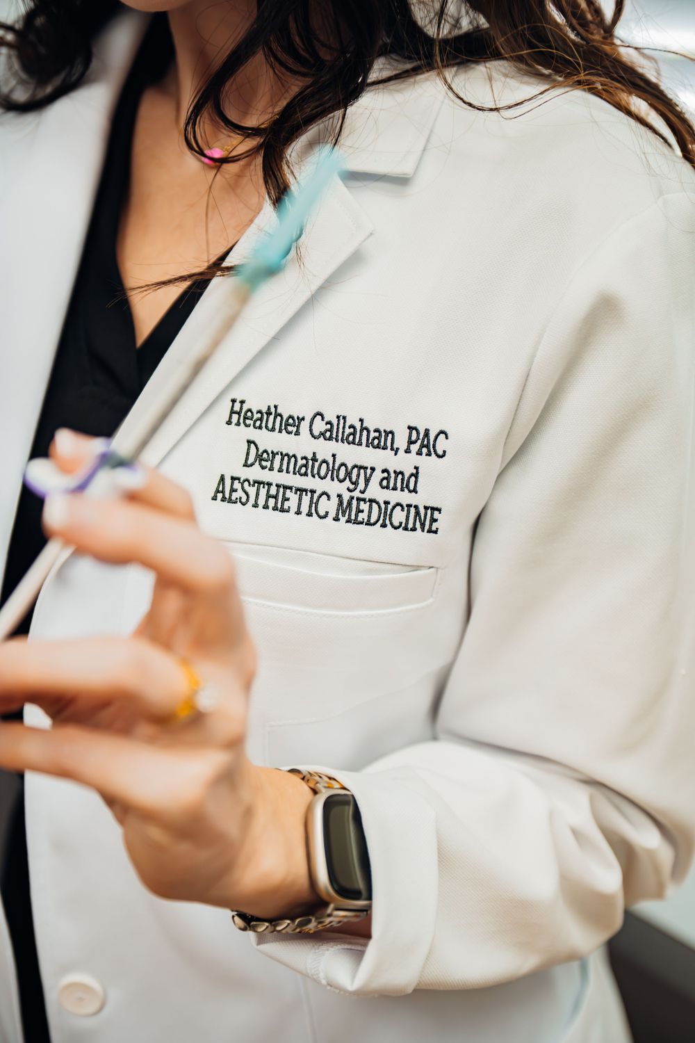 Medical professional in white coat with embroidered text for dermatology and aesthetic medicine practice.
