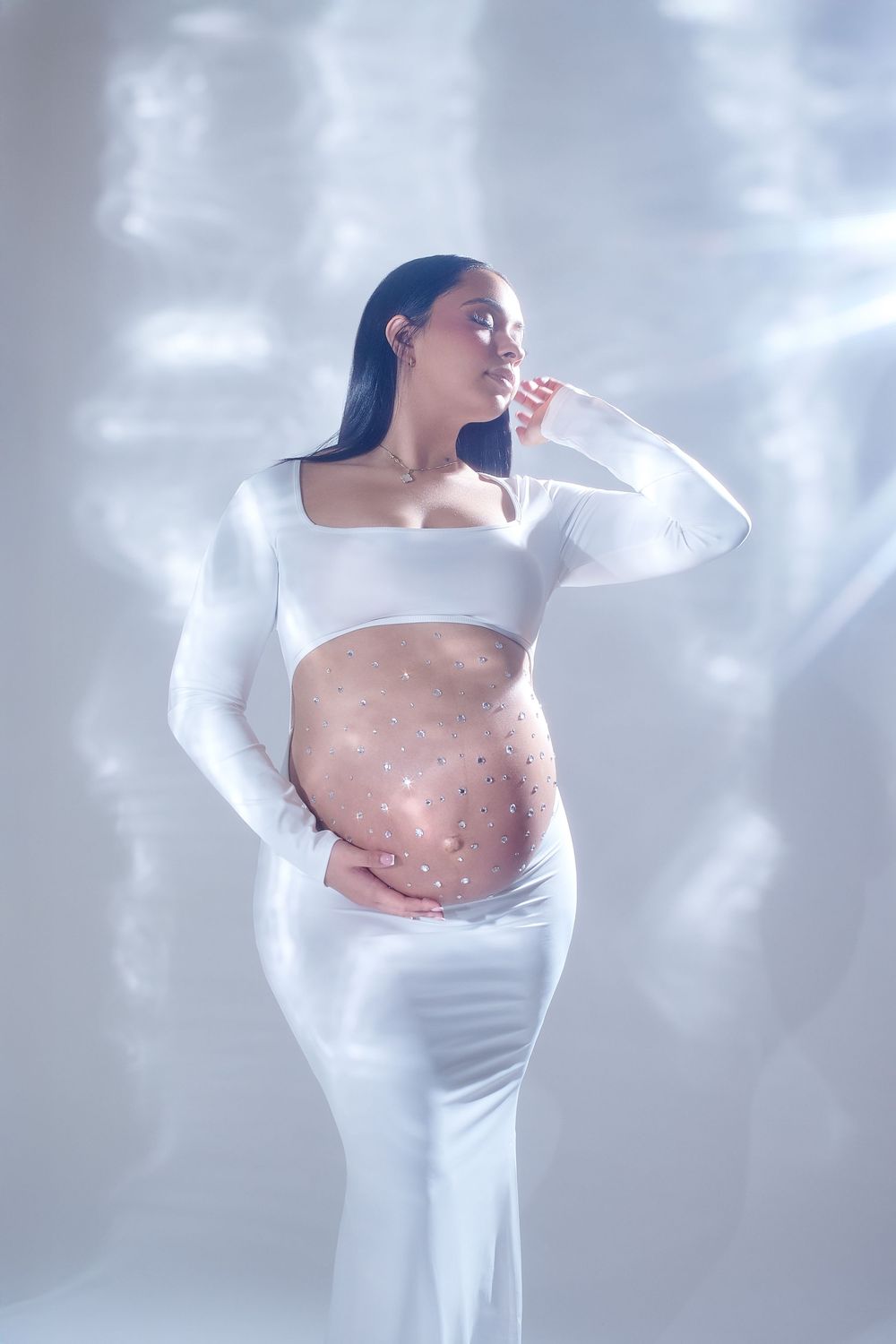maternity photo featuring an expectant mother in white dress with sparkles on her belly in dreamy lighting. gricels photography nutley nj