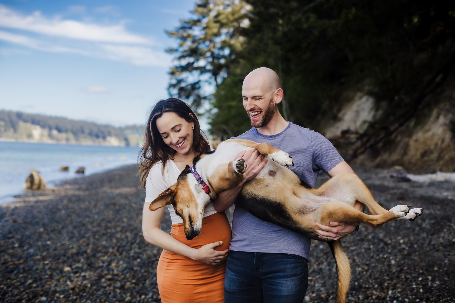 A couple holding their happy dogs on a rocky beach.