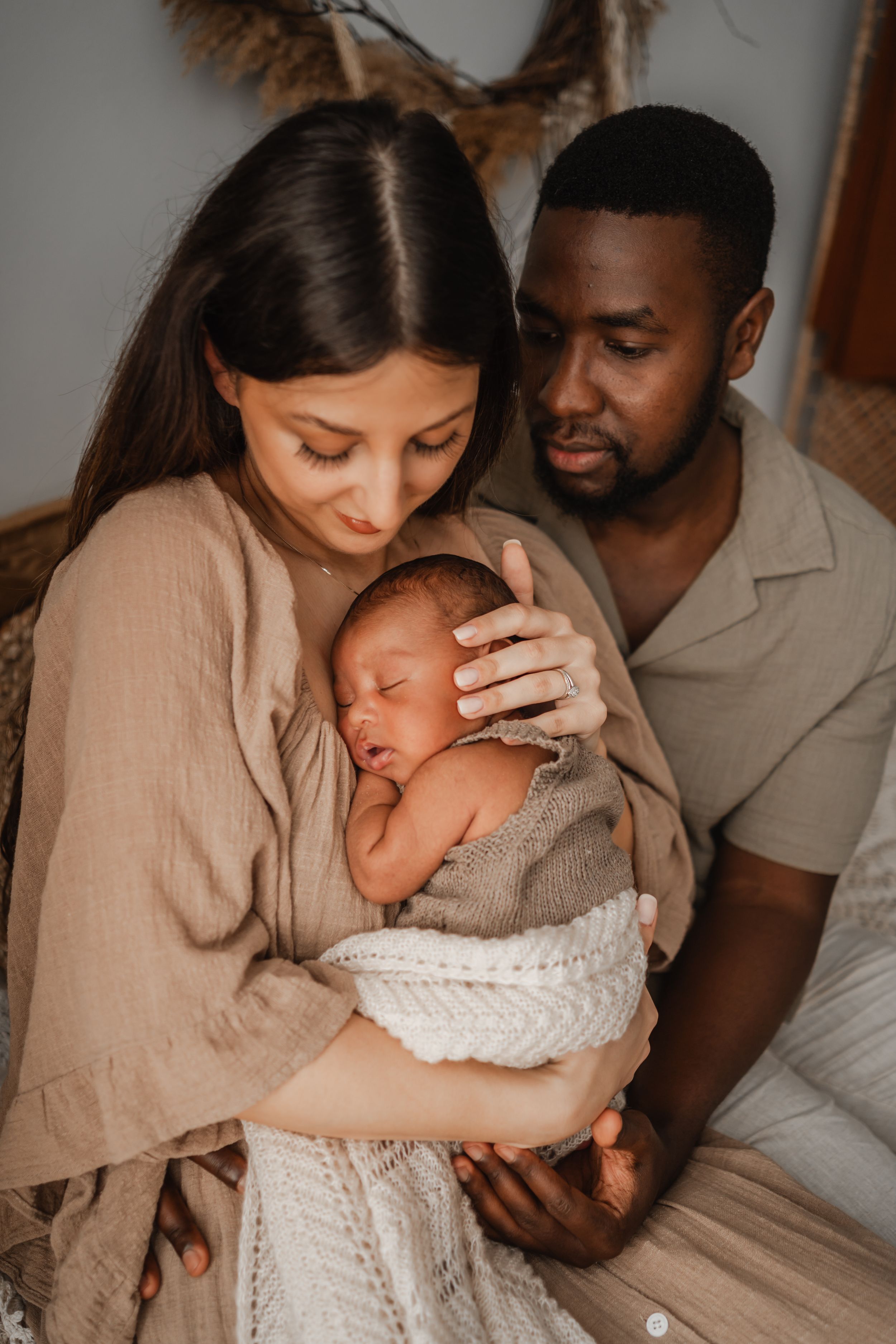 Mum and dad holding their newborn baby in a peaceful in-home newborn photography session, captured by their photographer in Portland, Dorset