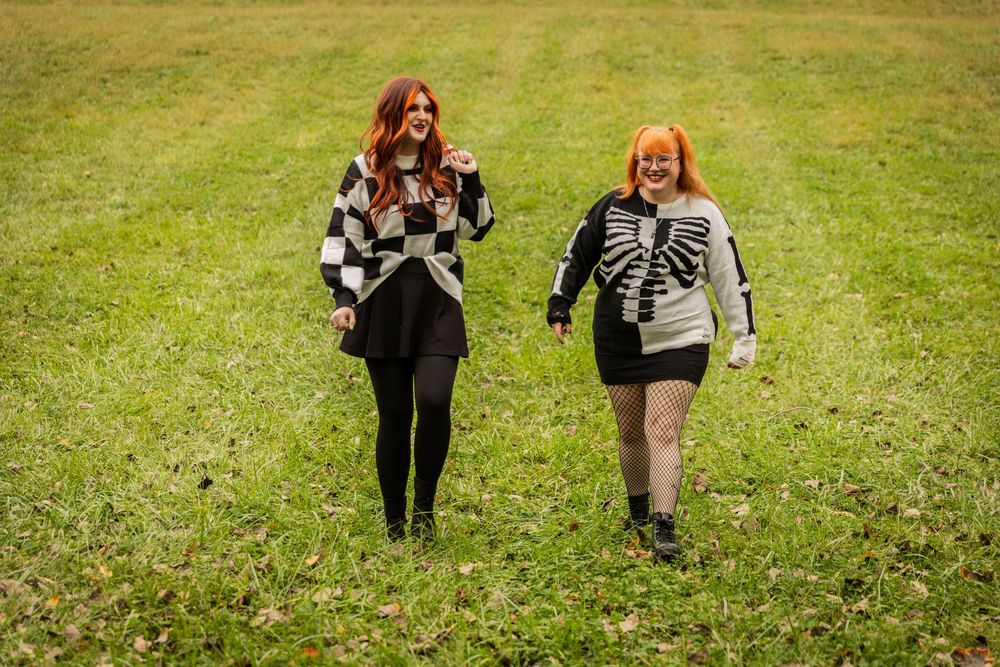 People walking on grass wearing black and white outfits in fall scenery.