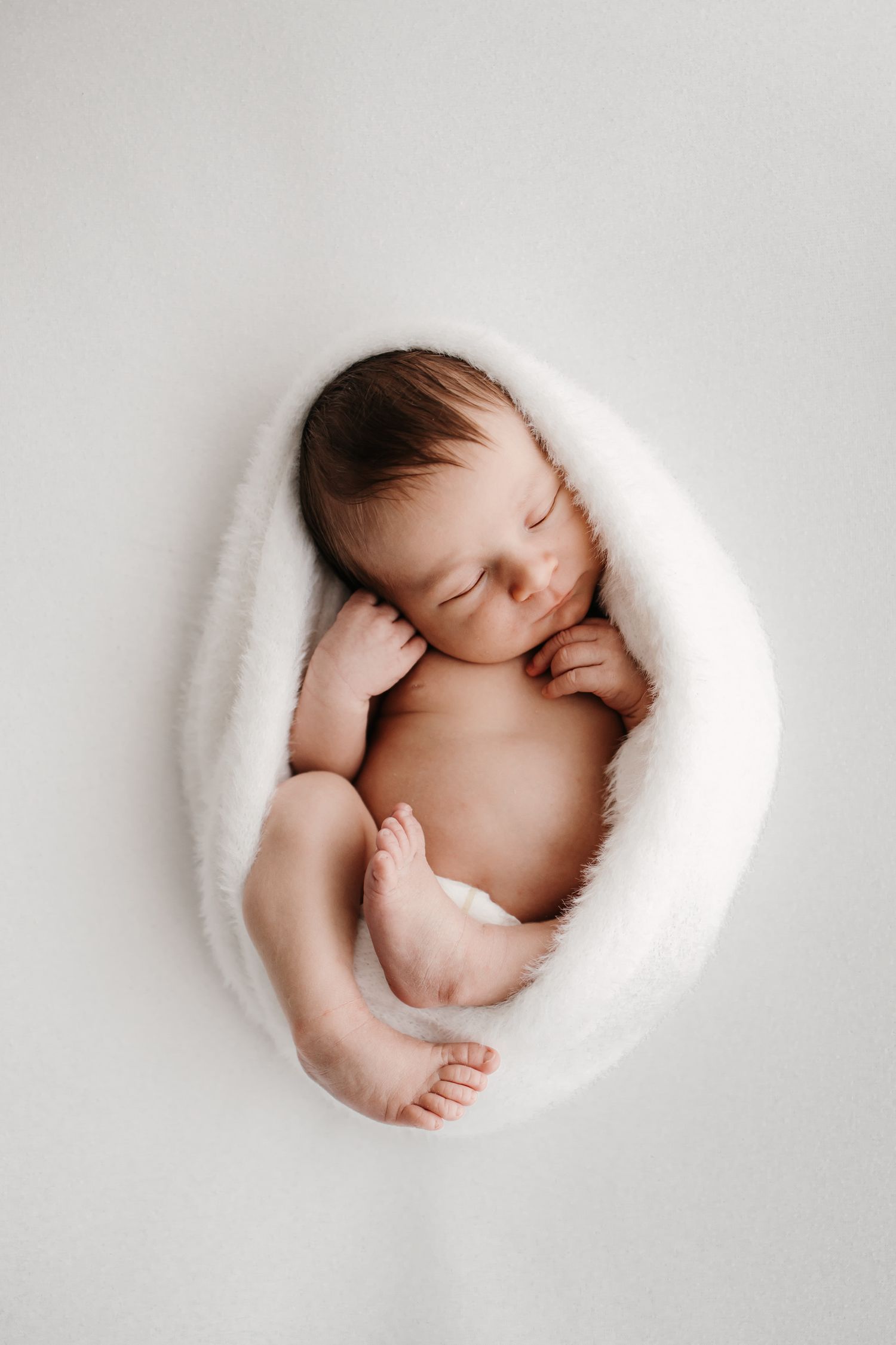 Baby in white polka dot outfit yawning while lying on soft blanket. Newbornkuvaus turku, newbornkuvaus raisio, newbornkuvaus naantali.