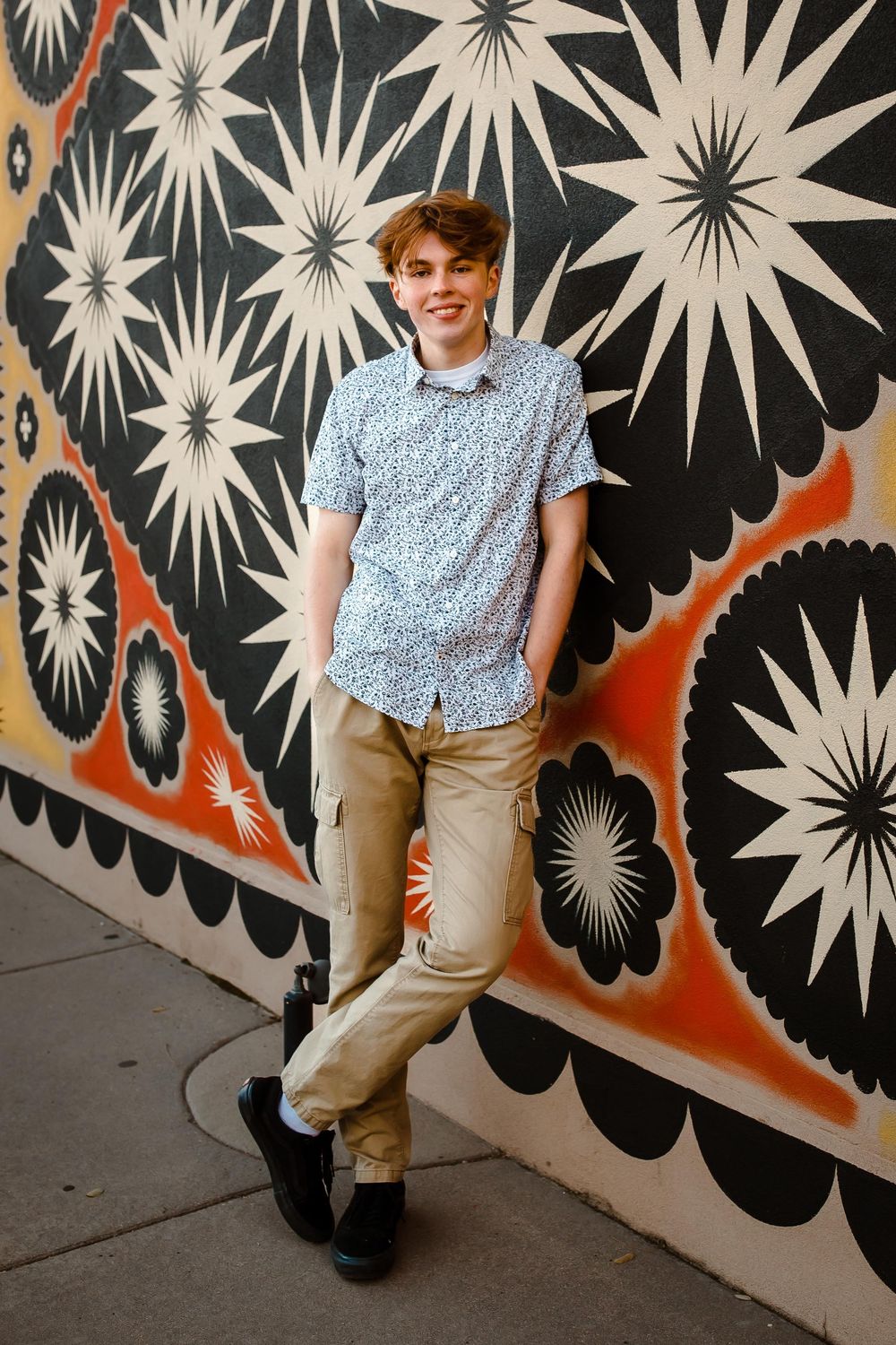 High school senior posing confidently in downtown Denver with colorful mural background
