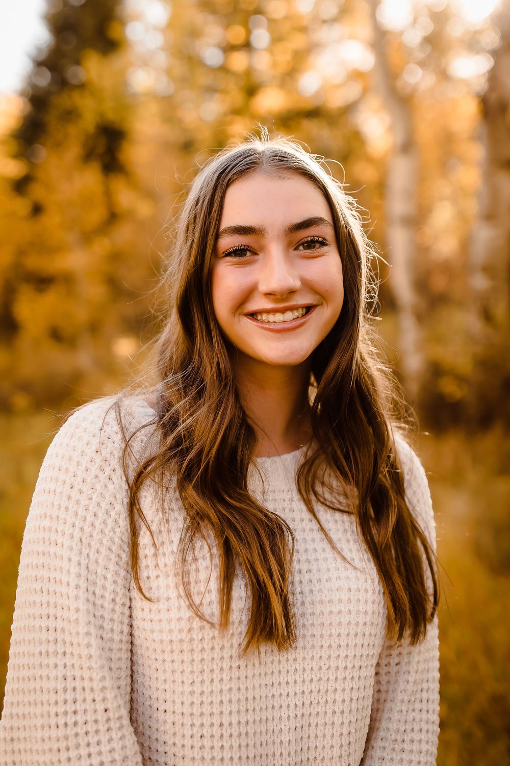A teenager smiles broadly in front of yellow aspen trees in Colorado