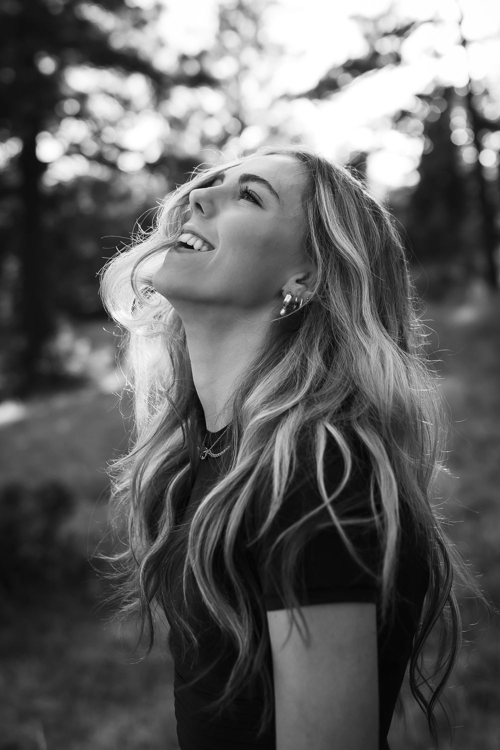 A black and white photograph of high school senior candidly laughing in the foothills at golden hour in Denver, Colorado