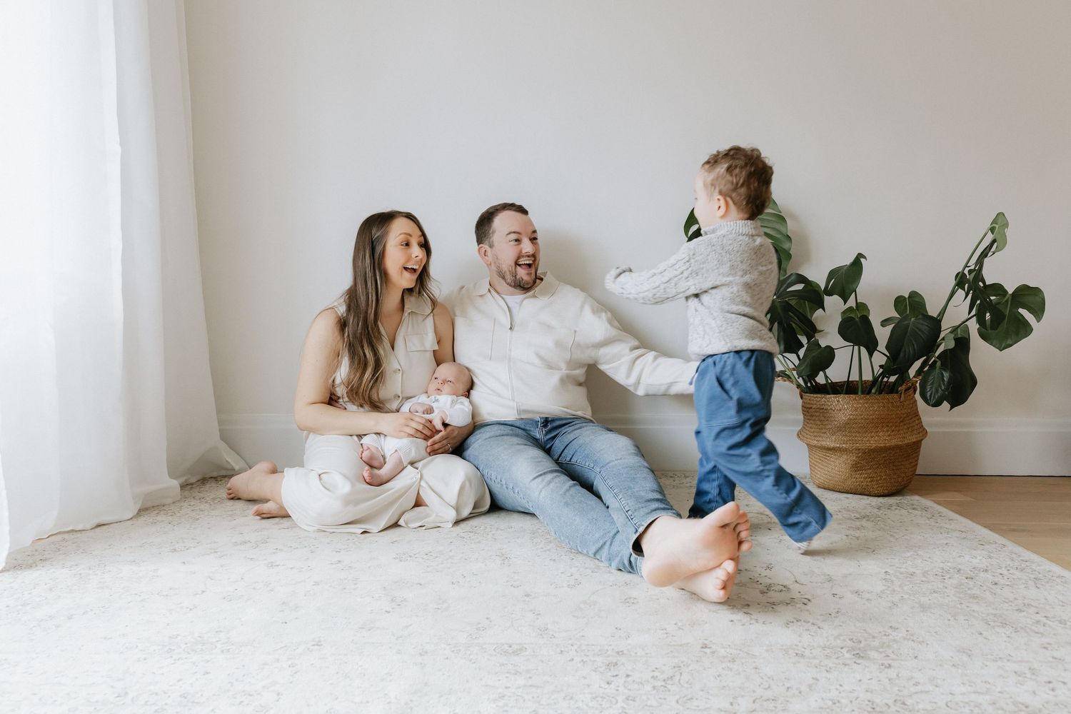 Family lifestyle photos showing relaxed moments on white floor in bright room.