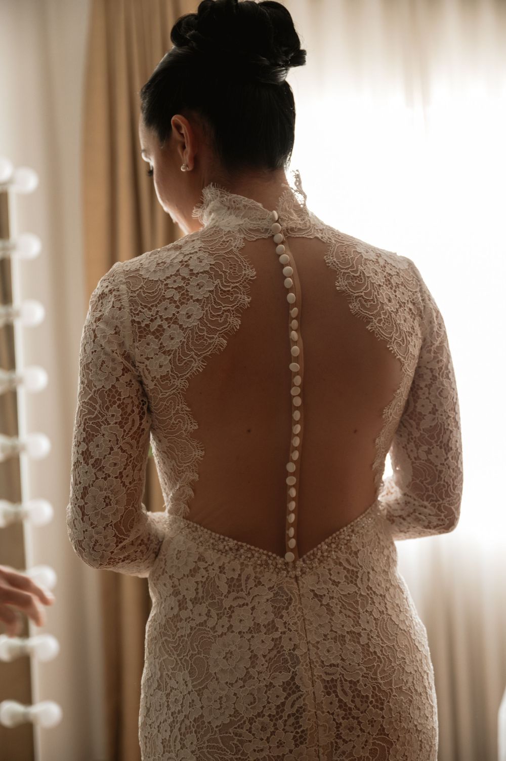 Close-up details of bride's lace dress showing intricate button-back design.