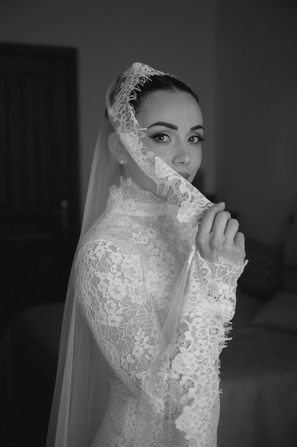 Dramatic black and white portraits of bride in lace wedding dress with veil.