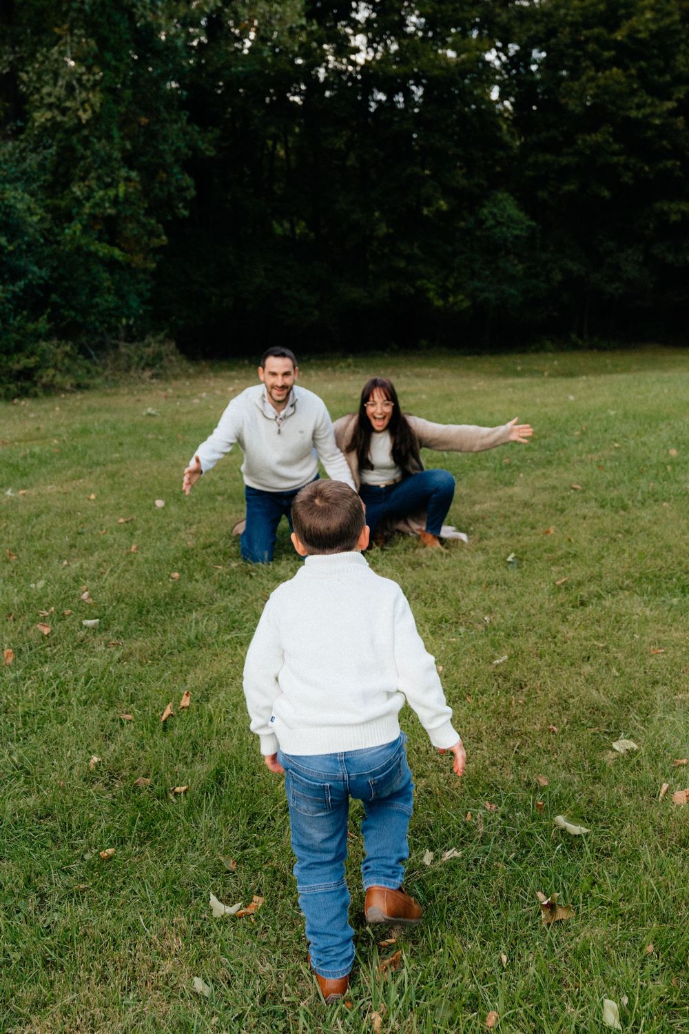 A playful family moment captured on a grassy hill during an autumn day.