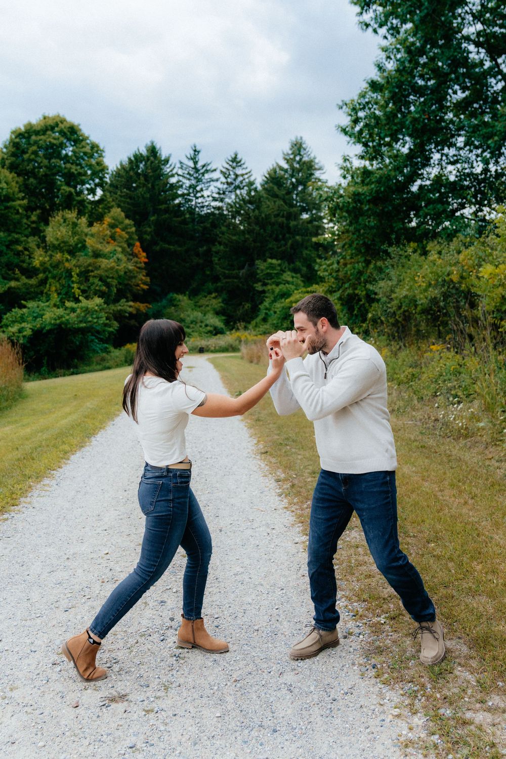 Couple playfully mock fighting in martial arts poses on a gravel path.
