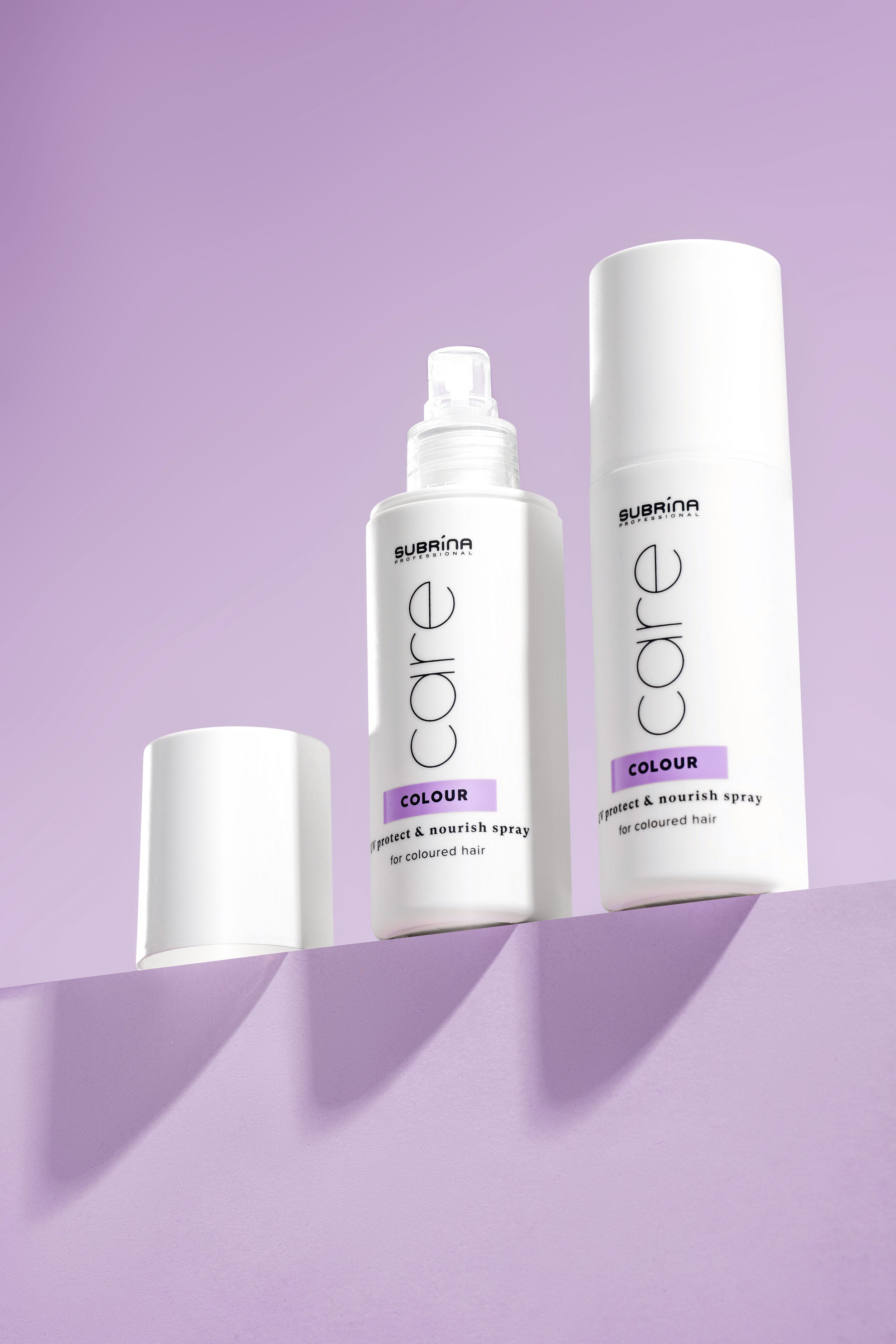 White cosmetic product containers arranged in a row against a purple background with dramatic shadows.