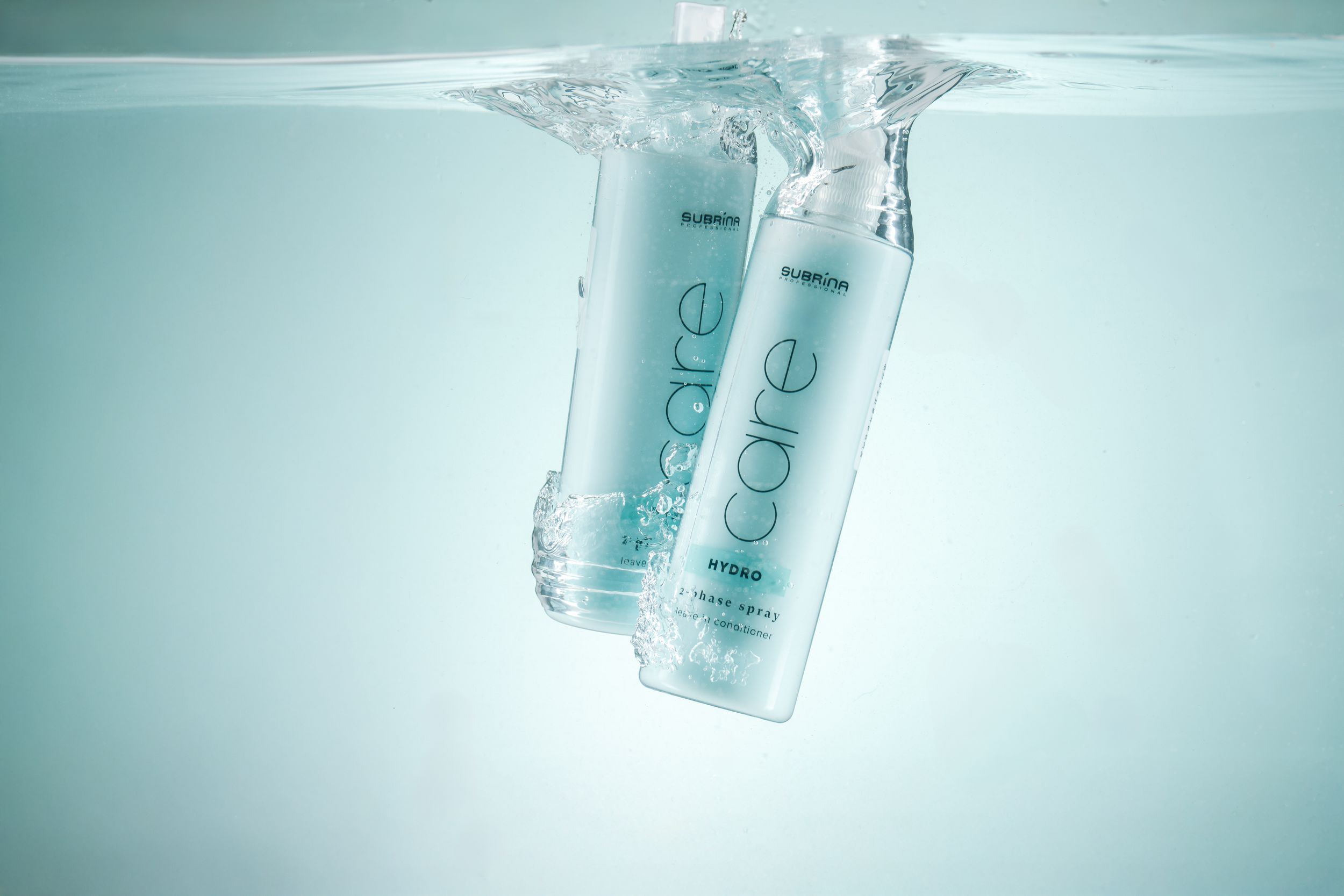 Floating cosmetic bottles in turquoise water creating a refreshing underwater product display.