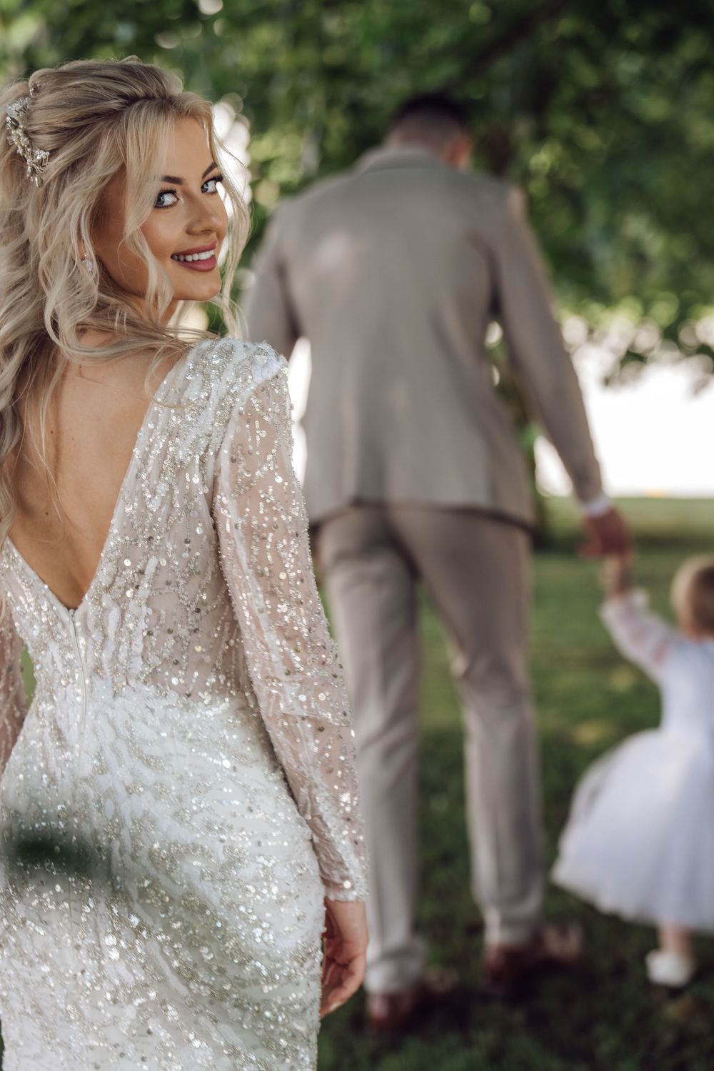 Sparkling lace wedding dress detail with delicate beading in natural outdoor setting.