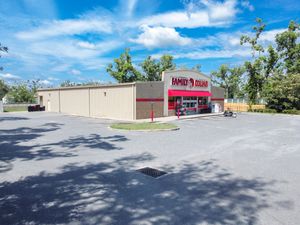 A commercial strip mall property with multiple storefronts and a spacious parking lot under bright blue skies.
