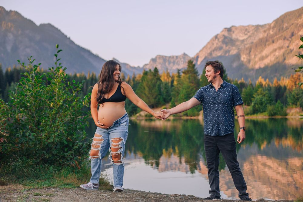Loving couple poses against mountain landscape during golden hour. Spokane Liberty Lake Photographer Maternity Photographer