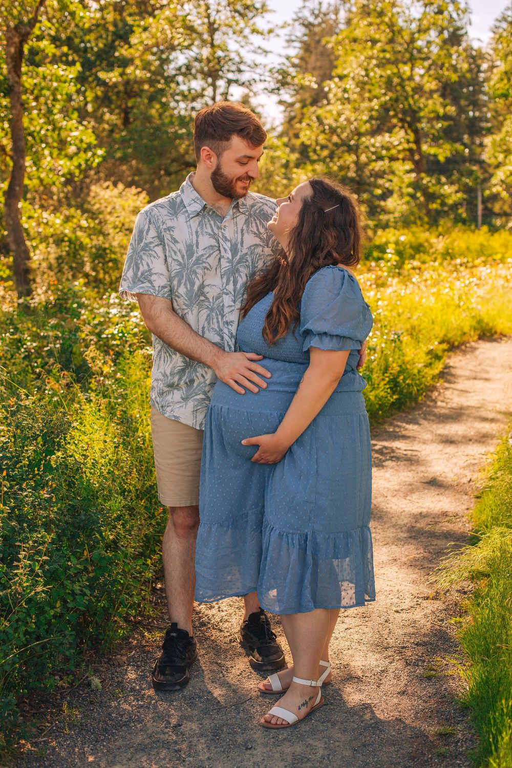 A couple shares intimate moments during their maternity photoshoot on a nature trail.  Spokane Liberty Lake Photographer Senior Photographer