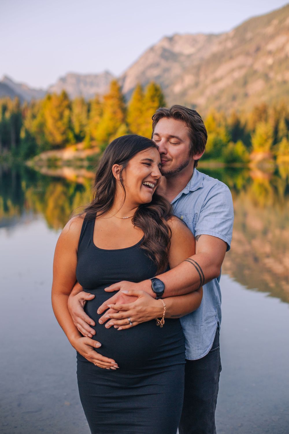 A couple embraces during a lakeside maternity photo session with golden hour lighting. Spokane Liberty Lake Photographer Maternity Photograp