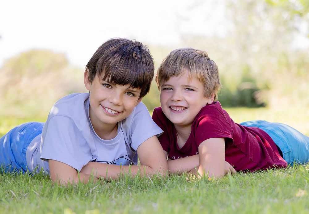 Two children lying on grass together on a sunny day.