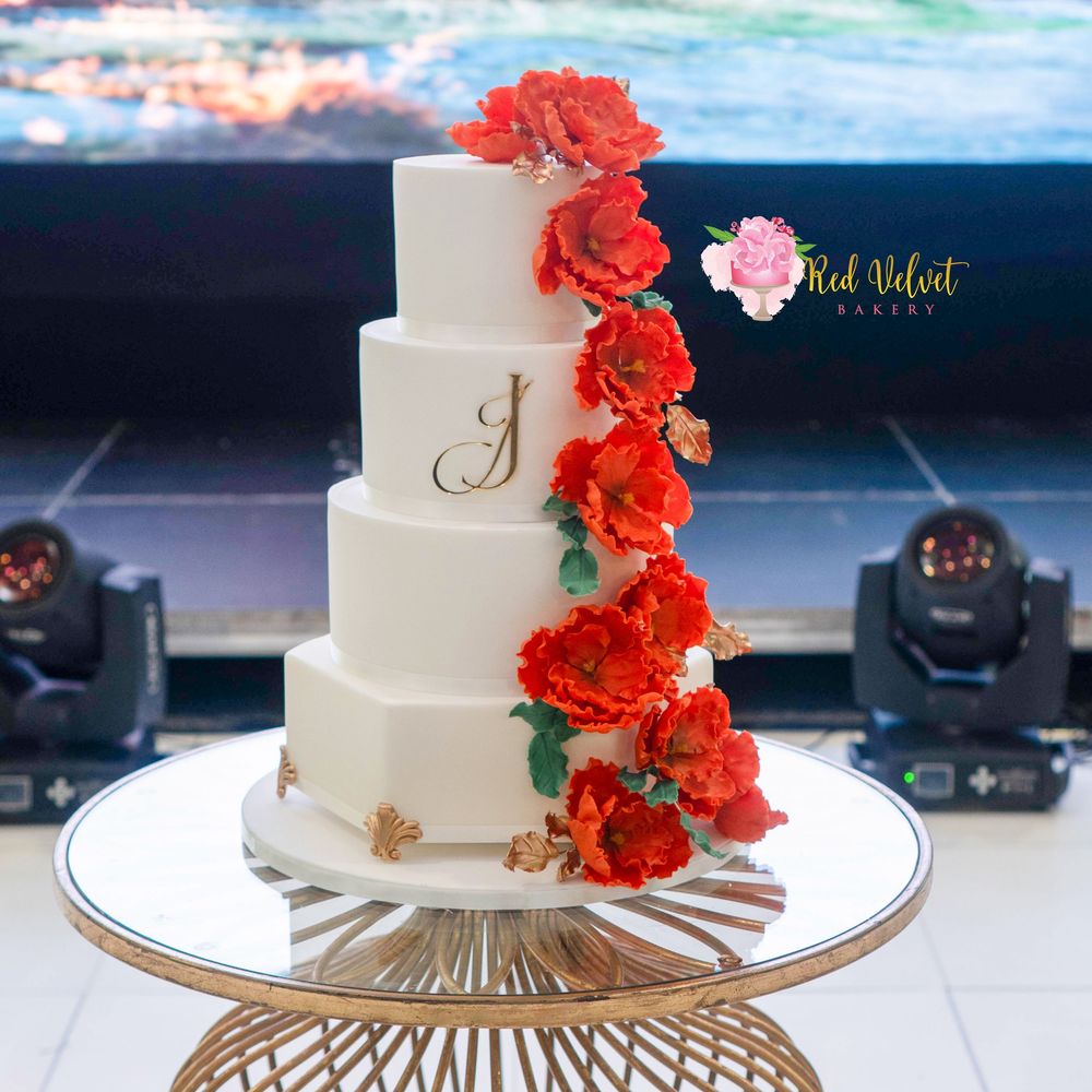 4 tier plain white fondant finished wedding cake, decorated with burnt orange sugar rogosa roses and a mixture of green and gold leaves