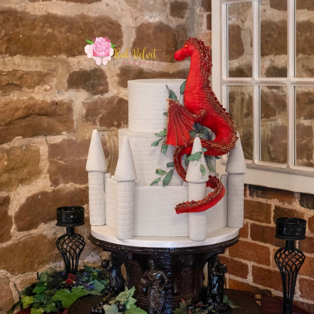3 tier castle themed wedding cake finished in green brick detailing, with a large red and gold dragon on the side