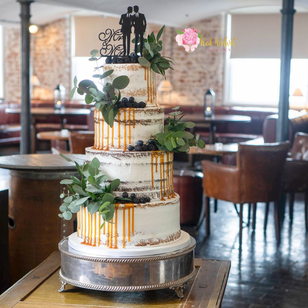 4 tier semi naked wedding cake finished with salted caramel drip effect and lots of green foliage