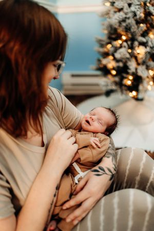 A peaceful moment with sleeping newborn by Christmas tree lights.