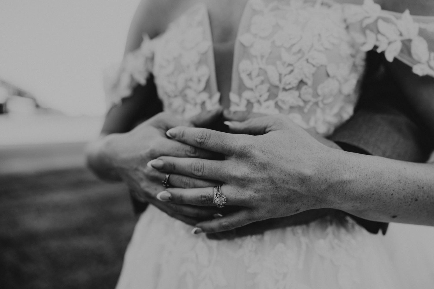 Romantic moment between newlyweds in formal attire against moody outdoor backdrop.