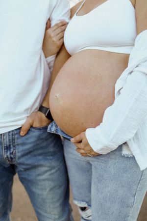 Close-up of pregnant belly with hands tenderly cradling the bump.