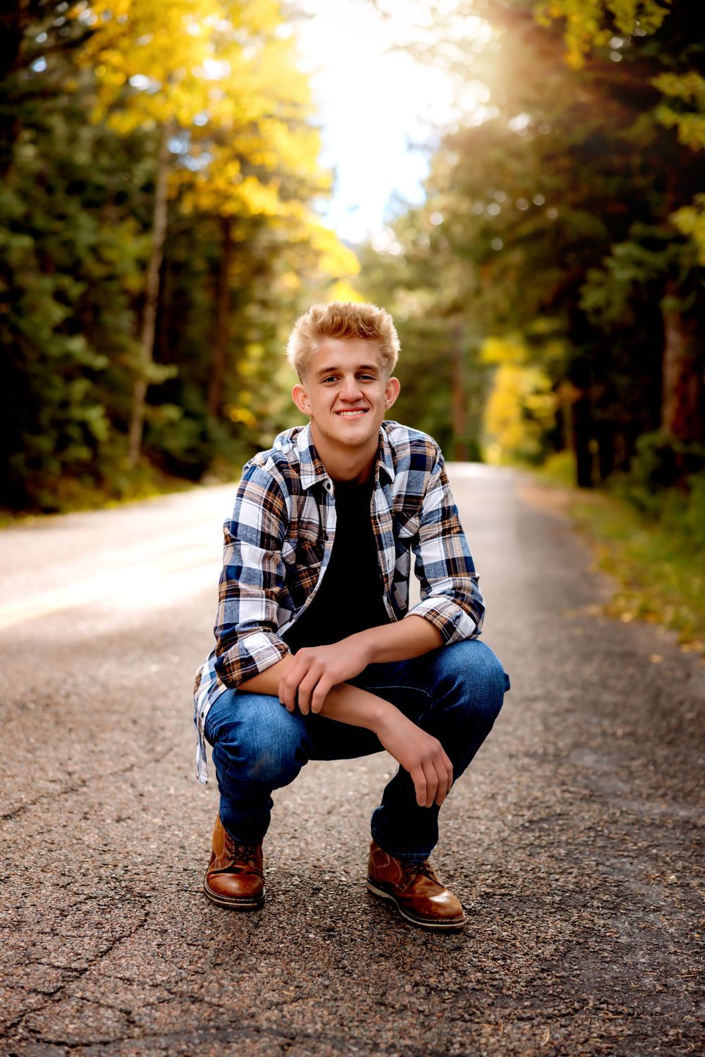 A casual outdoor portrait session on a gravel road with autumn trees creating a golden backdrop .Senior Pueblo Photographer