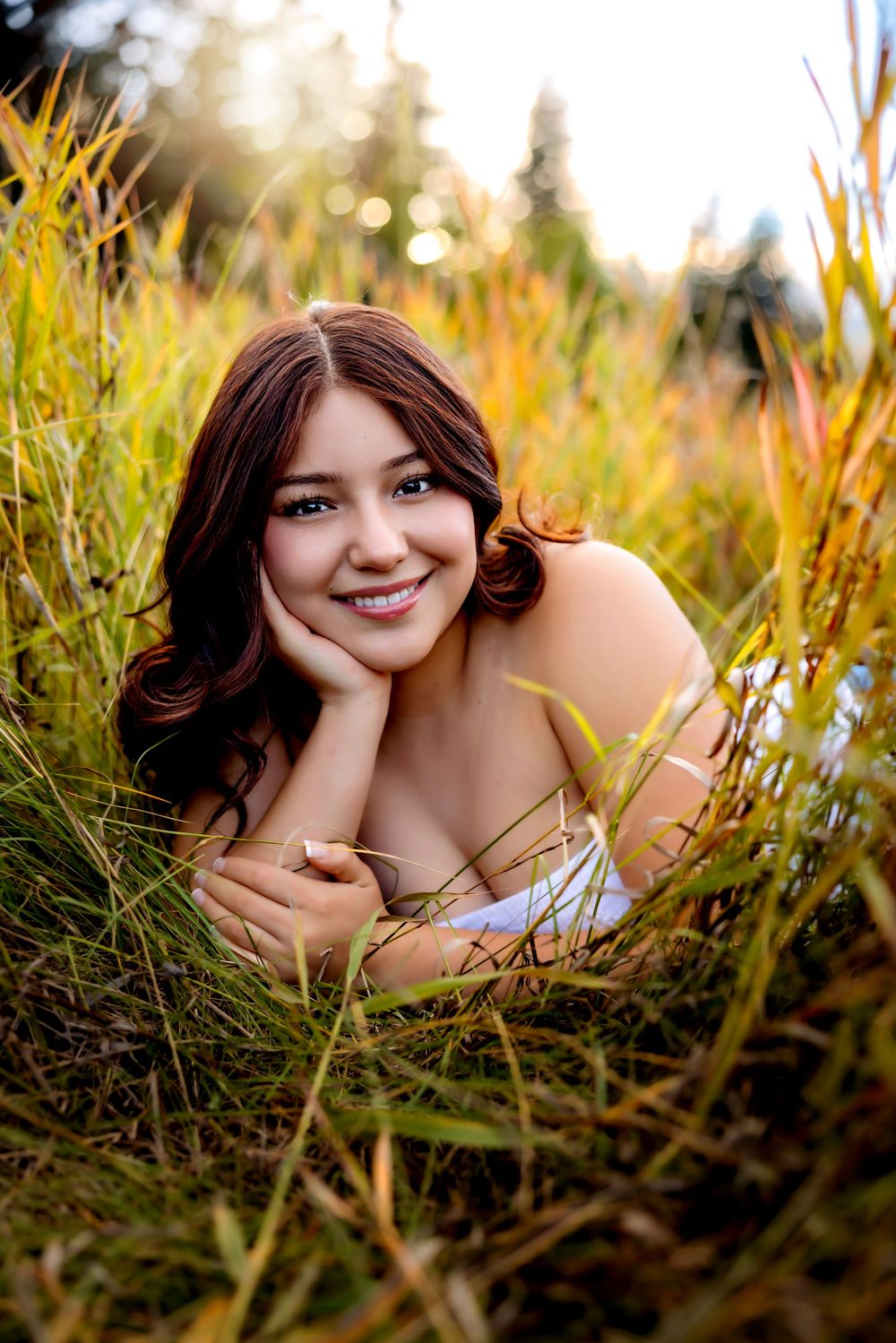 Portrait photography in golden field with tall grass and warm sunlight creating a dreamy outdoor atmosphere. Senior Pueblo Photographer