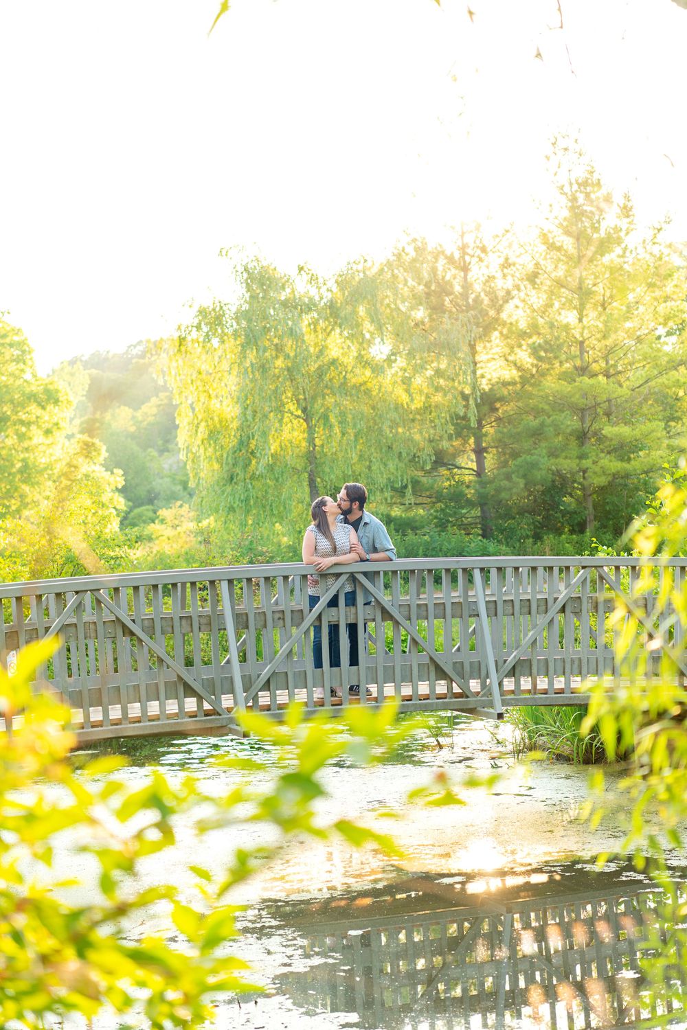 A couple shares an intimate moment on a wooden bridge over a lily pond at sunset at Waterworks Park in St Thomas.