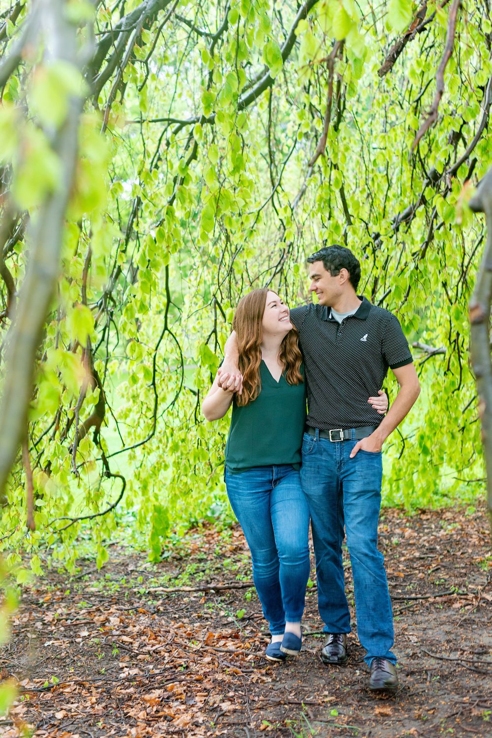 Couple walking and laughing together under hanging willow branches at Springbank Gardens in London Ontario.