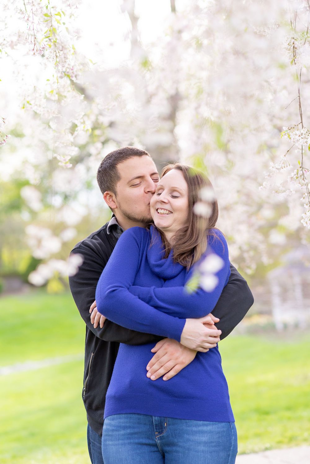 A couple shares a tender embrace in front of blooming cherry blossoms at civic gardens in London ontario.