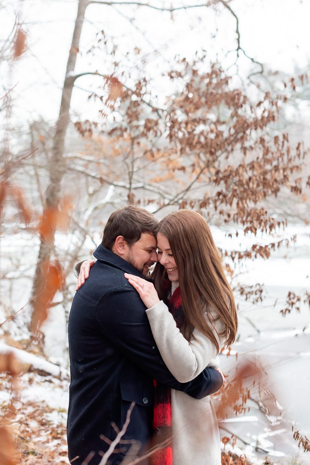 Romantic winter portraits with snow-covered trees in the background at Springwater Conservation Area.