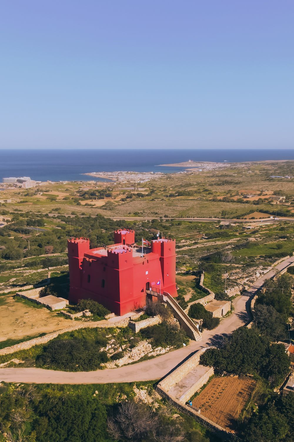 Red St Agatha's Tower stands prominently on Malta's rugged coastal landscape.