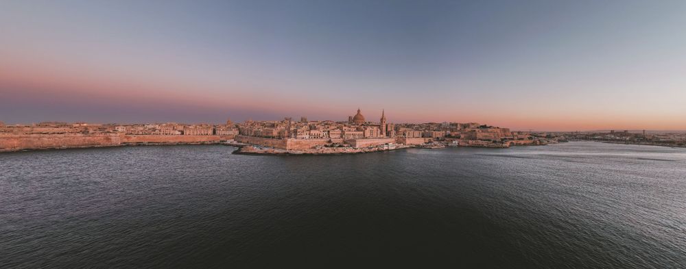 Panoramic coastal cityscape with dramatic sunset colors over the Mediterranean Sea.