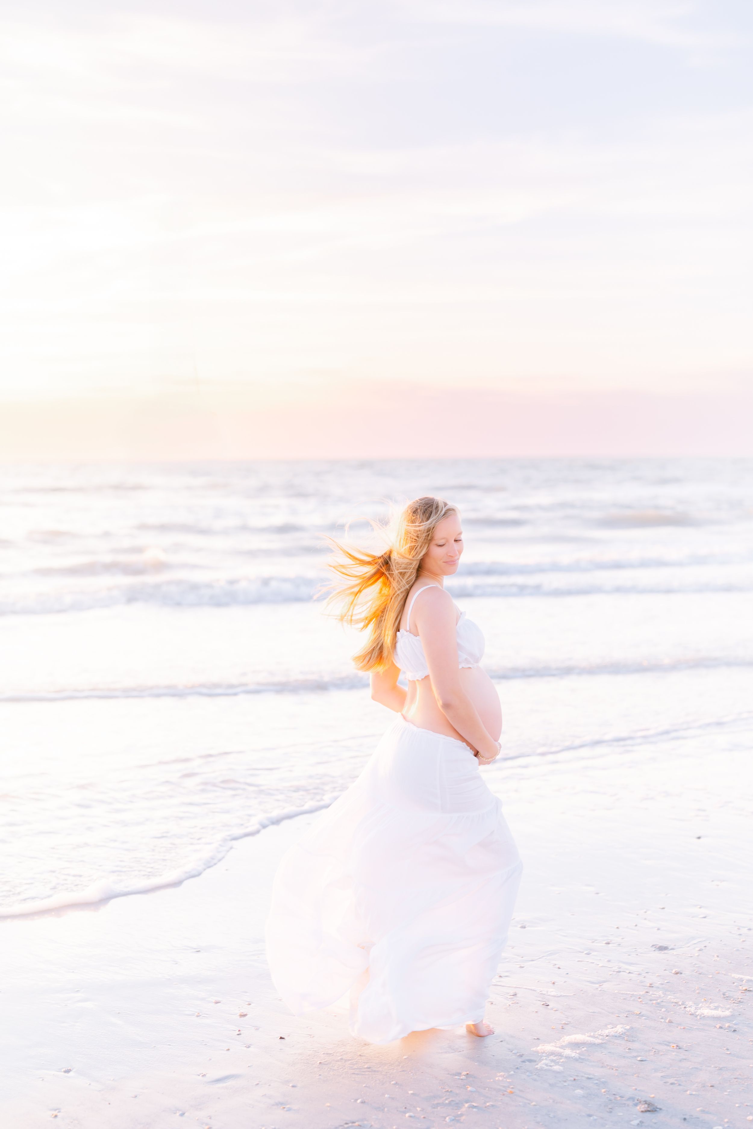 mom looking over her shoulder in a two piece maxi set with her pregnant belly in the golden hour glow during her maternity photoshoot