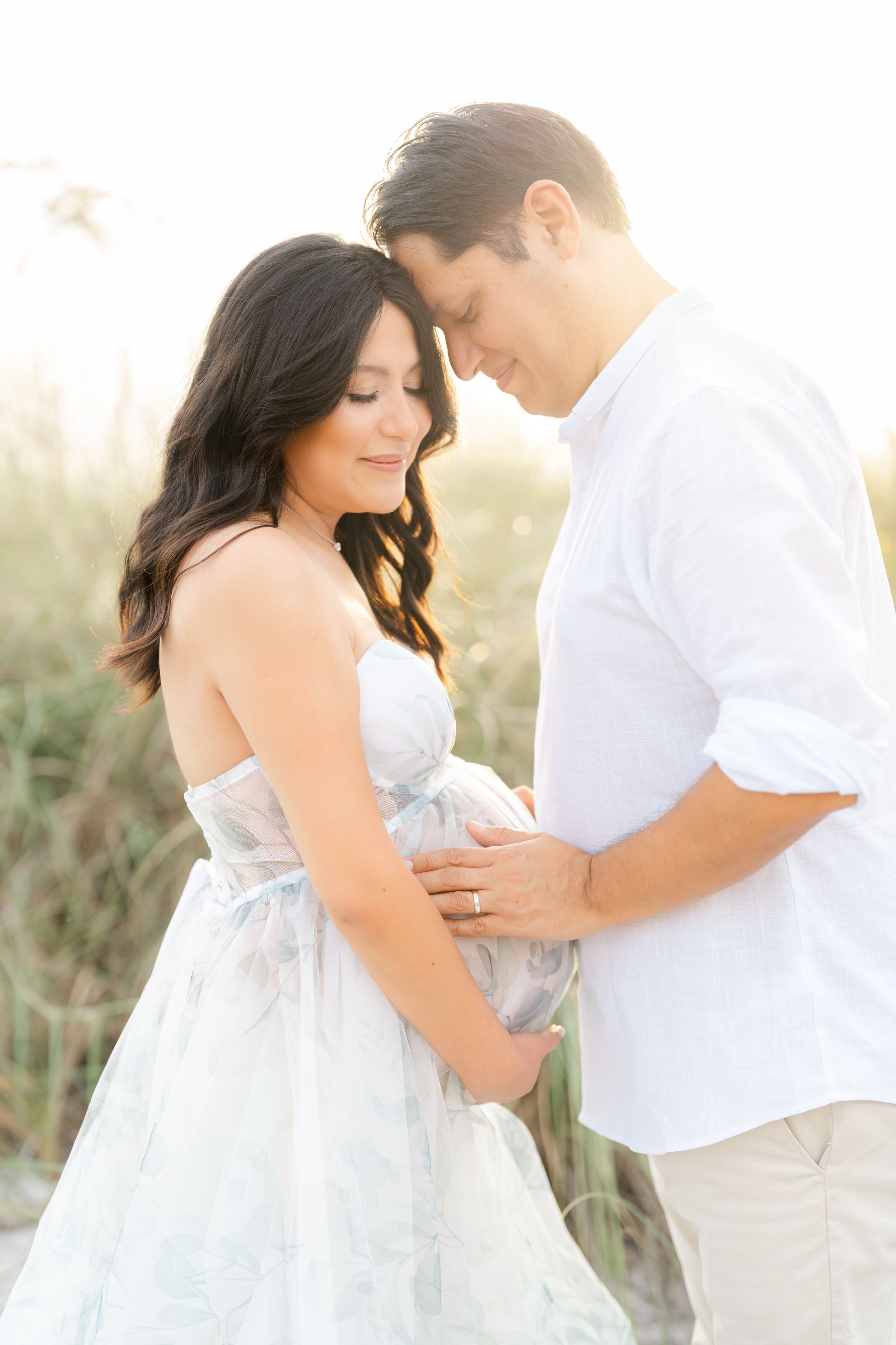 maternity photoshoot on st. Pete beach at golden hour mom and dad embracing romantic