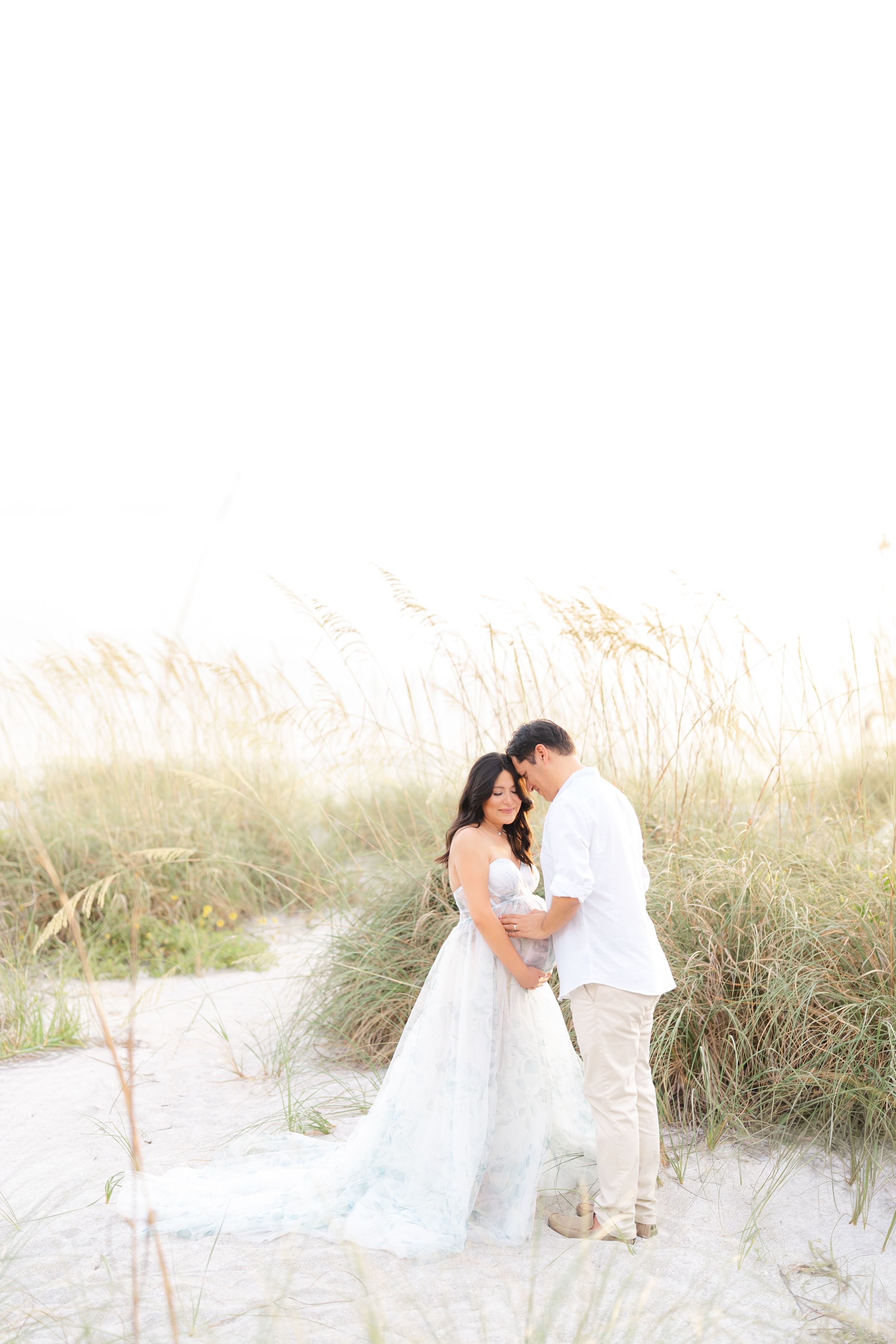 maternity photoshoot on st. Pete beach at golden hour mom and dad embracing romantic