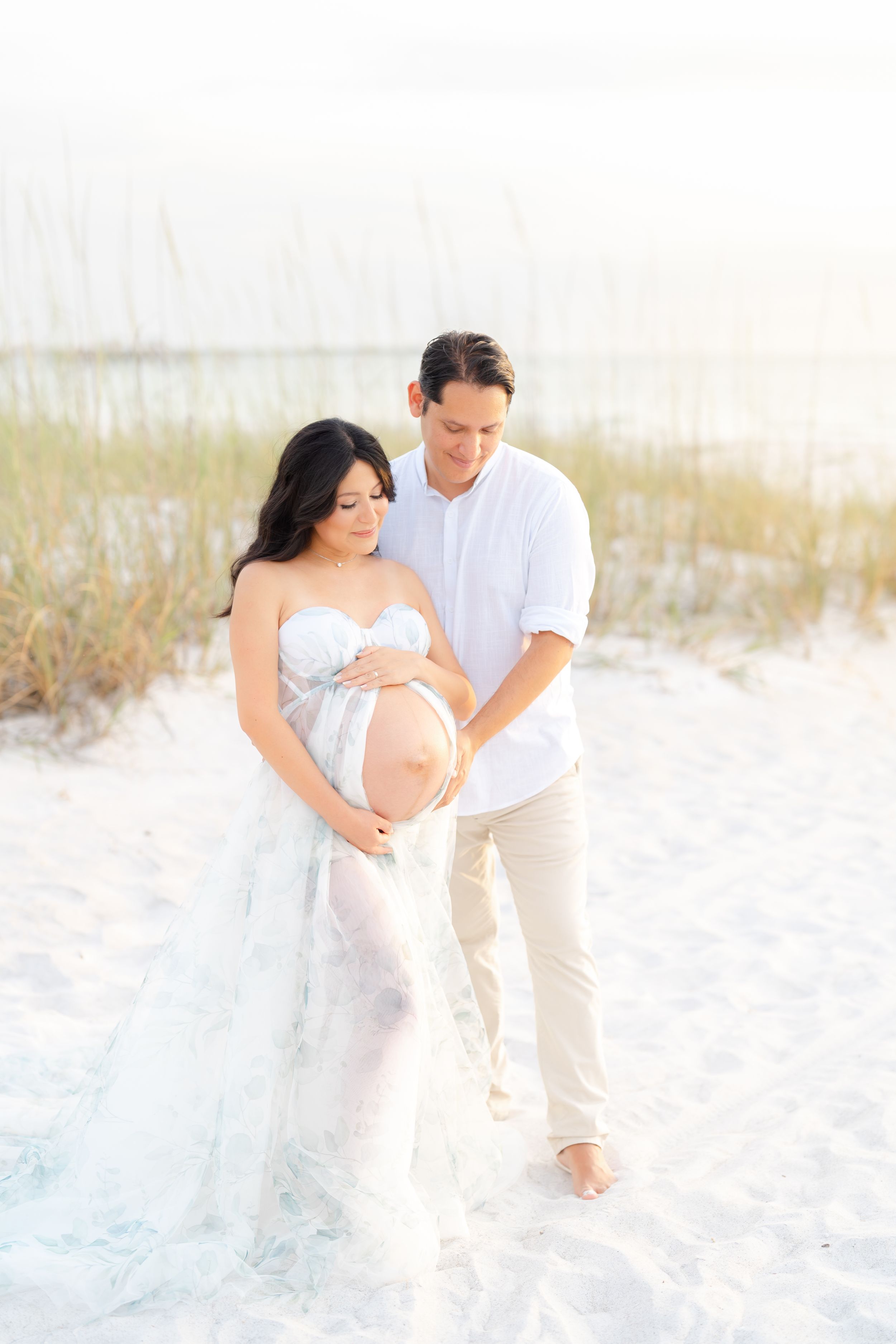 maternity photoshoot on st. Pete beach at golden hour mom and dad embracing romantic