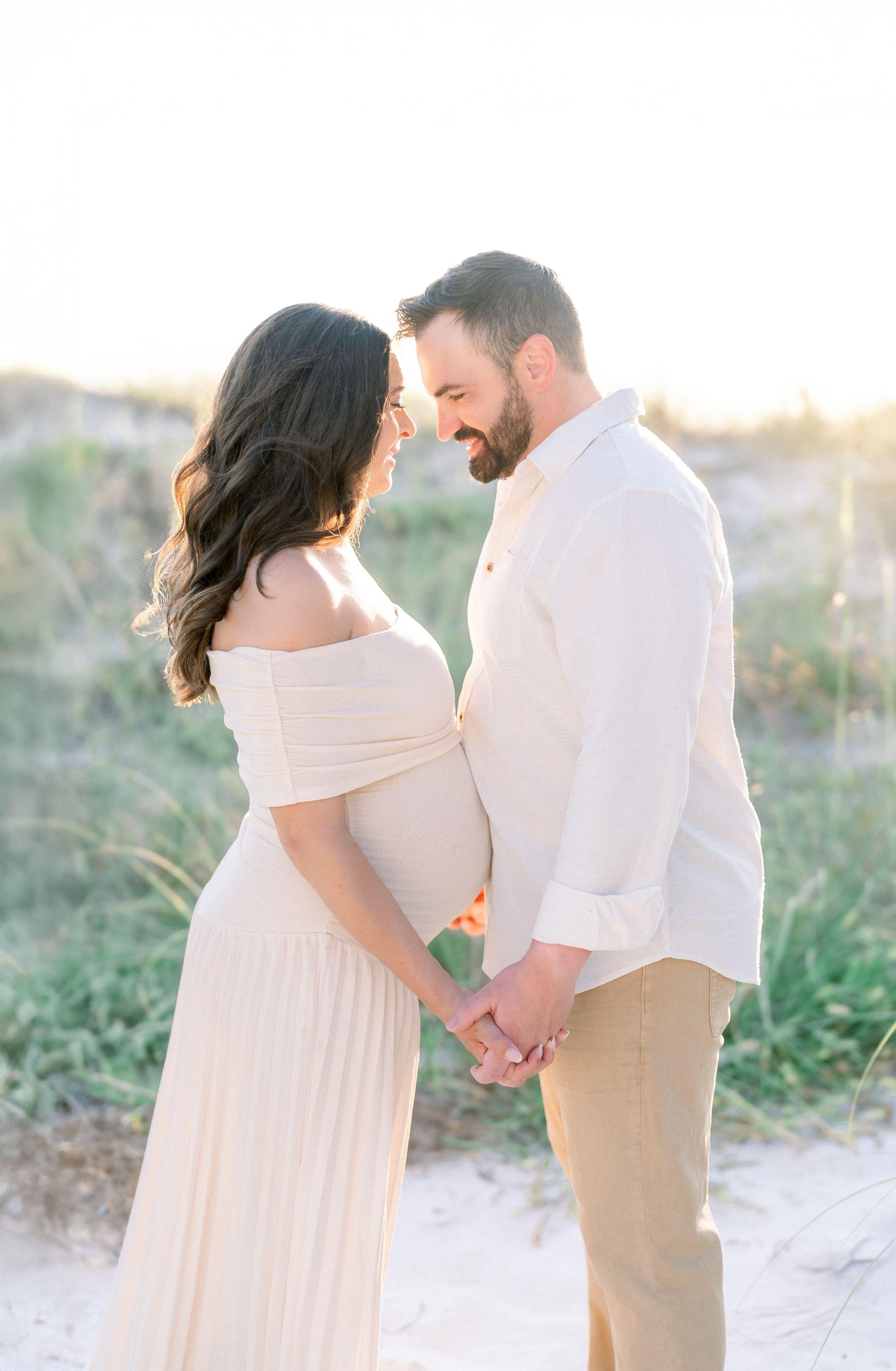 maternity session on St. Pete Beach at golden hour mom and dad hand in hand