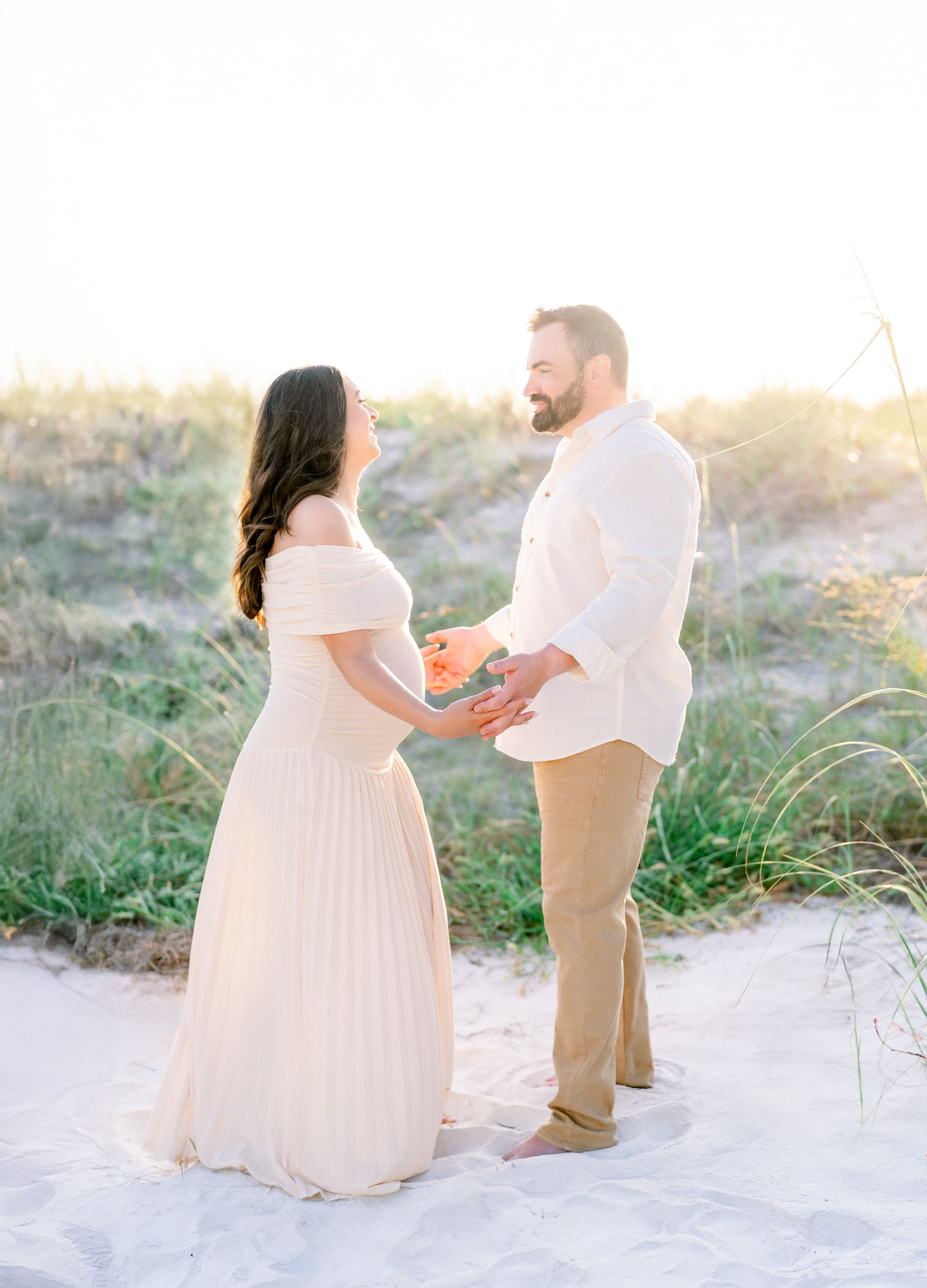 husband and wife dancing during their maternity session at golden hour on St. Pete Beach