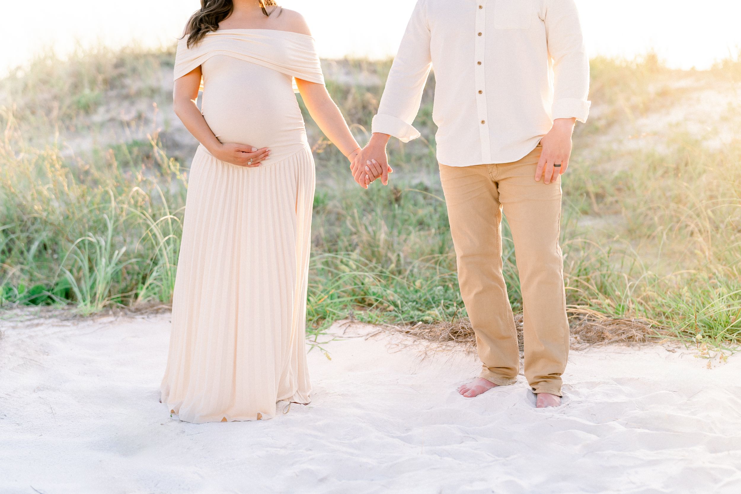 details photo of parents holding hands while mom is cradling her belly during their maternity photoshoot on St. Pete Beach Don Cesar