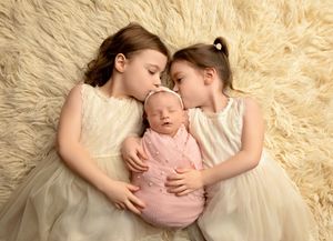 Newborn baby cuddled by siblings during a family newborn photography session in Tilton NH