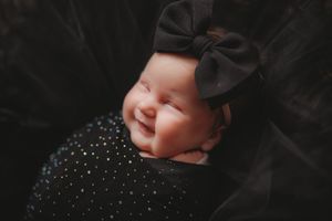 Artistic black and white newborn portrait with soft lighting and delicate headpiece.