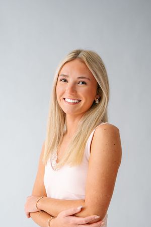 Casual studio portraits in light pink tank top against grey background.