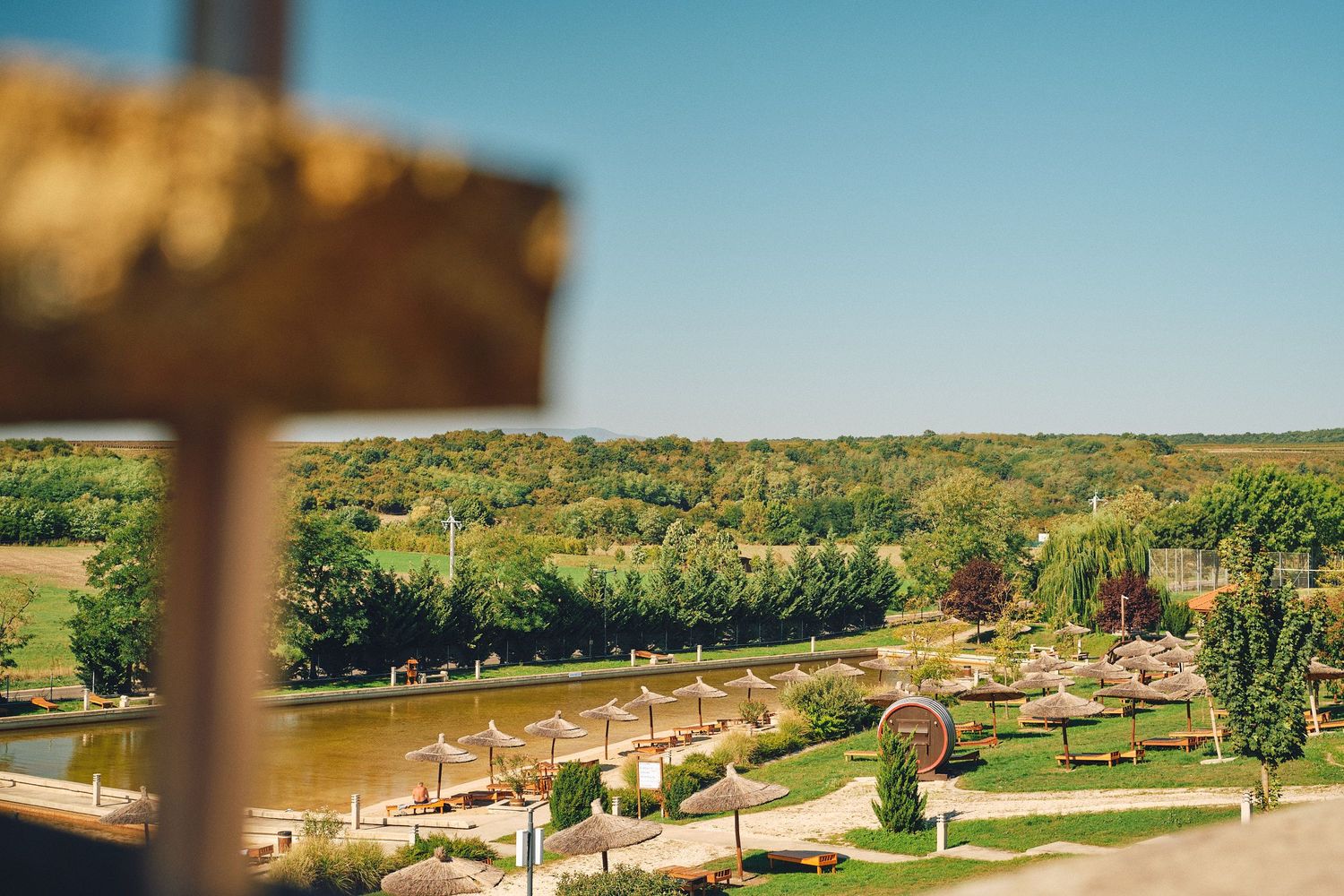 A panoramic view of a golf course with rolling green fairways stretches across a sunny landscape.