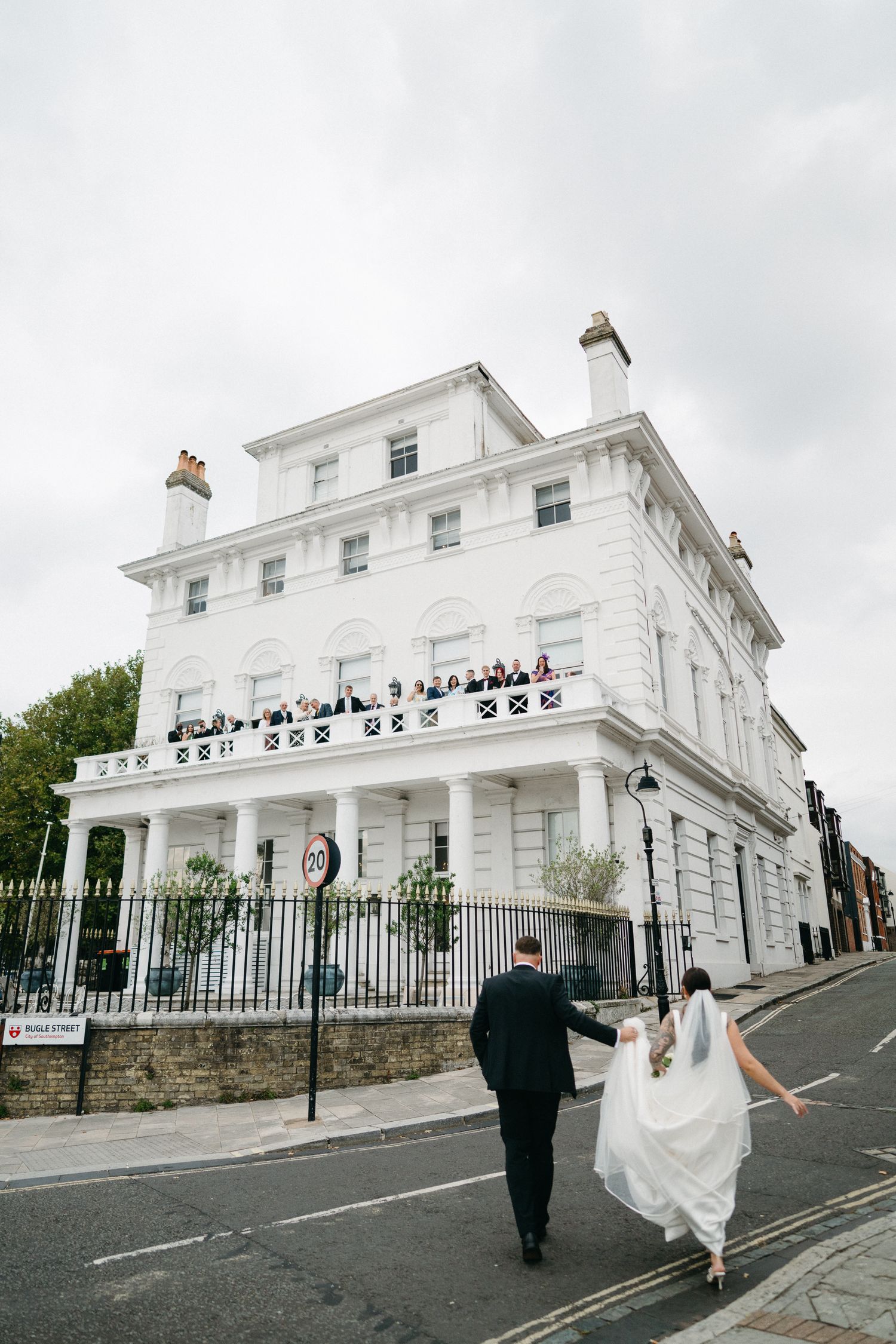 A series of wedding photos showing a couple walking near a grand white Georgian-style building with black iron railings.