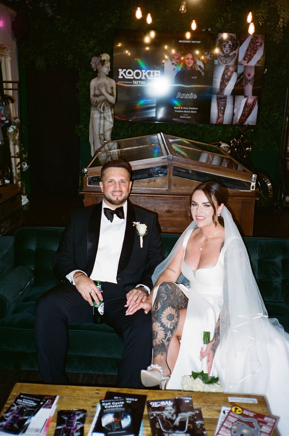 Newlyweds at their wedding reception share a celebratory toast with champagne glasses at a rustic wooden table.